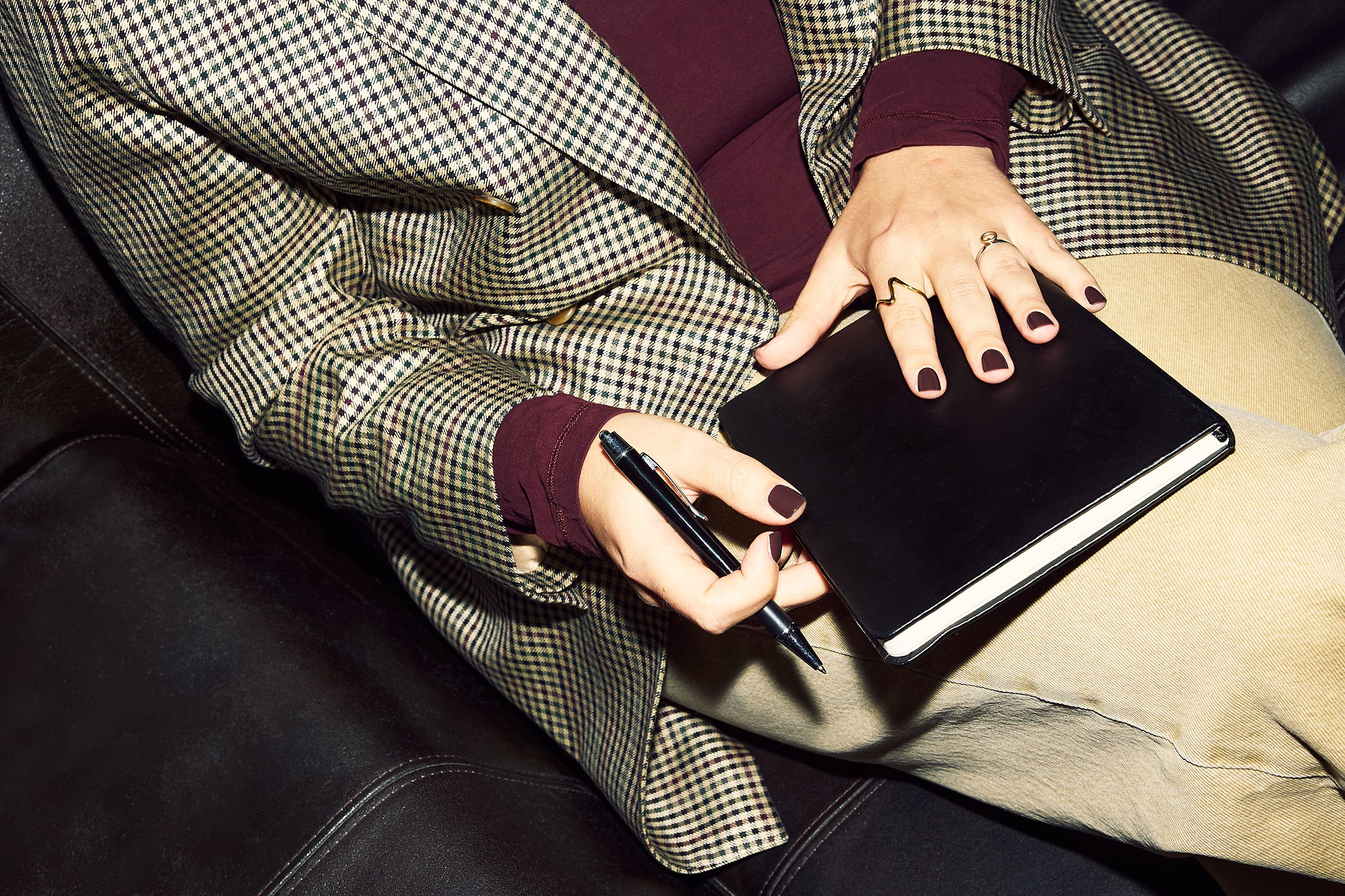 Nahaufnahme von Händen, die ein Notizbuch halten, Person im karierten Mantel.